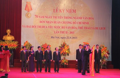 Ủy viên Bộ Chính trị, Bí thư Ban Chấp hành Trung ương Đảng, Trưởng Ban Tuyên giáo Trung ương Đinh Thế Huynh gắn Huân chương Hồ Chí Minh lên lá cờ truyền thống của ngành VHTTDL